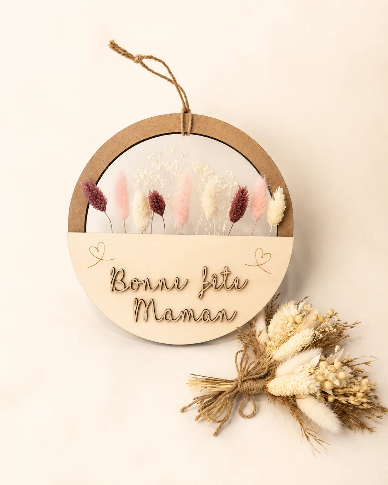 Cadre rond en bois avec fleurs séchées roses et blanches et le message « Bonne fête Maman »