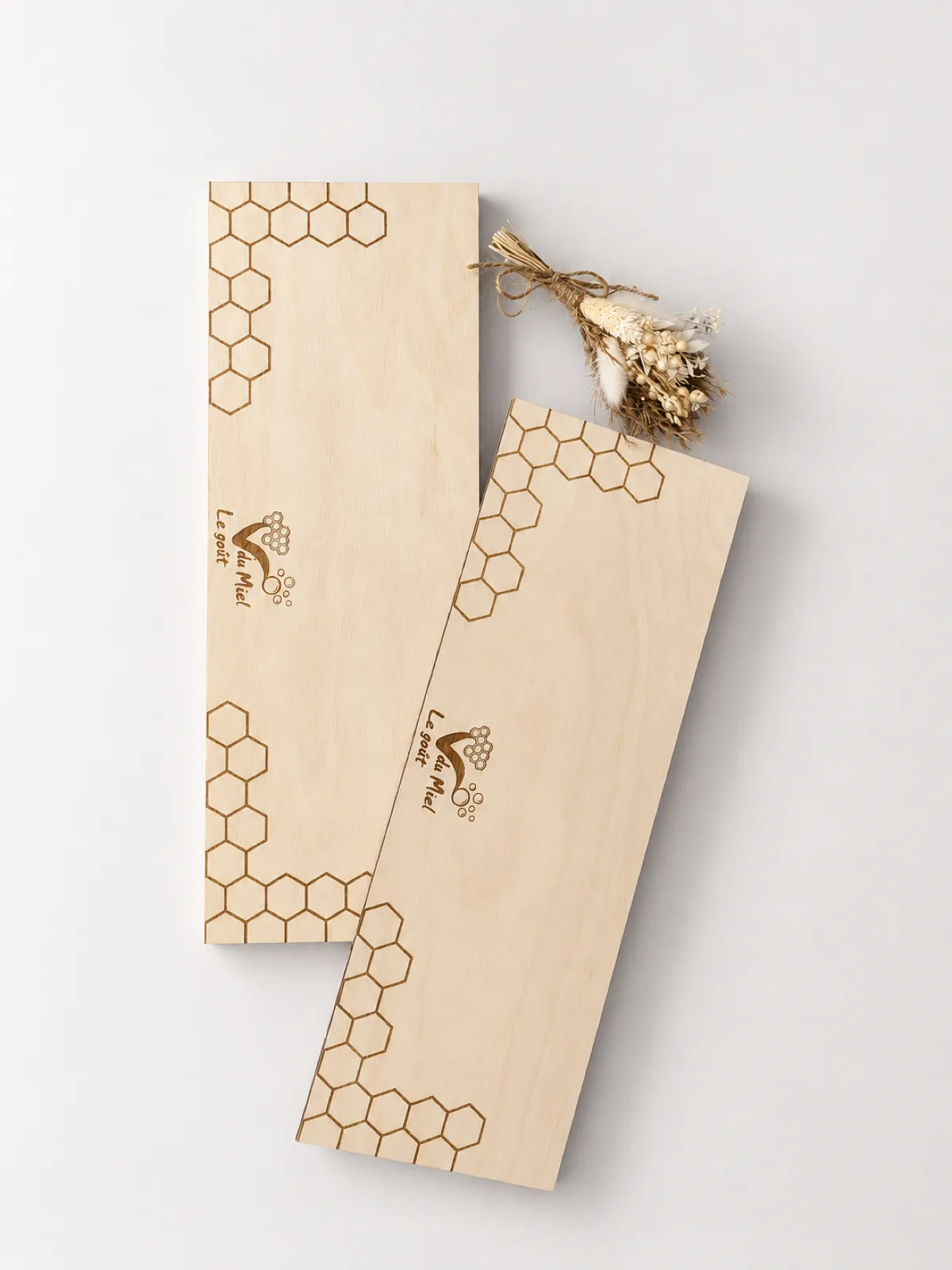 Deux planches en bois clair gravées au laser d’un motif d’alvéoles et d’un logo